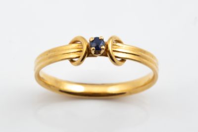 gros plan d'une bague en or avec une pierre en saphir