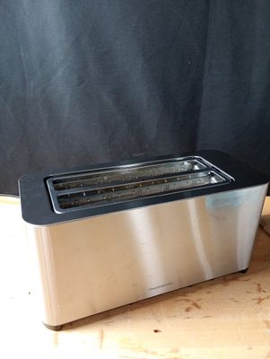 une image représentant un grille-pain posé sur une table, sur fond noir
