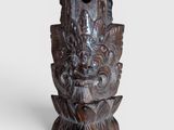 an old carved wooden sculpture of a face on a pedestal