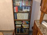 une bibliothèque avec des livres dessus, à côté d'un fauteuil