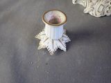 a white candle holder with a gold rim on a table