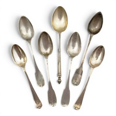six cuillères en argent sont disposées en cercle sur une surface blanche