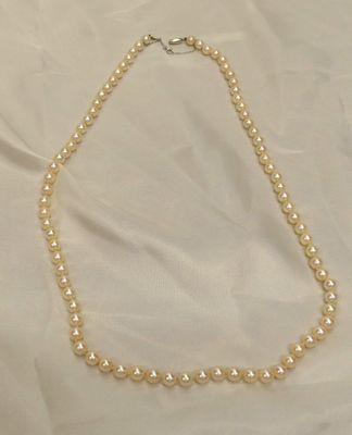 a close up of a pearl necklace on a white cloth