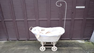 Berceau en rotin laqué blanc sur un pietement à grosses roul…