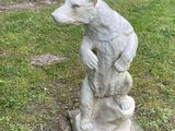 a statue of a bear sitting on a rock in the grass