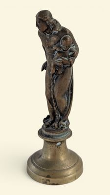 statue en bronze représentant une femme tenant un enfant dans ses bras, posée sur un socle