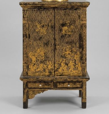 an old wooden cabinet with a gold decoration on top of it