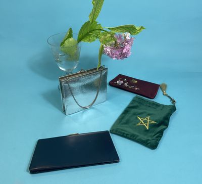 a glass vase with a flower in it next to a purse and a wallet