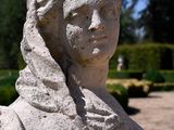 a stone statue of a woman in the middle of a garden