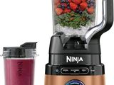 a blender with a blender next to a cup of fruit