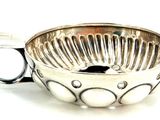 a silver bowl with a spoon in it on a white surface