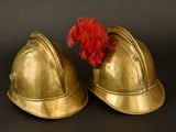 pair of gold helmets with red feathers on a black background