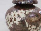 a vase with a lid that has flowers on it