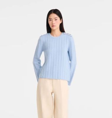 une photo d'une femme portant un pull bleu clair et un pantalon beige