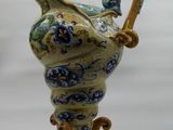 a blue and yellow vase with a handle on a stand