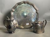 un plateau en argent sur lequel se trouve une théière en argent et un autre plateau en argent sur lequel est posée une théière en argent
