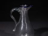a glass pitcher sitting on a table with a black background