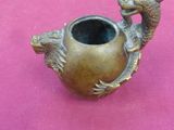 un vase en bronze orné d'un dragon sur un fond rose