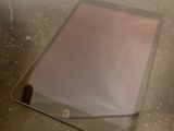 une tablette posée sur une table recouverte d'une vitre