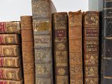 several old books are lined up in a row on a white surface