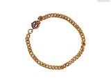 Le bracelet en chaîne d'or est orné d'une breloque en forme de cœur.