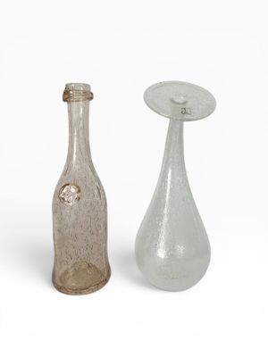 deux bouteilles en verre posées l'une à côté de l'autre sur une surface blanche
