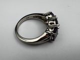 a close up of a silver ring with purple stones on it