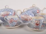 four cups and saucers on a table with a teapot