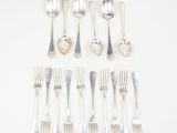 a lot of silver spoons and forks laid out on a table
