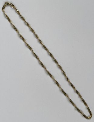 un gros plan d'un collier avec une chaîne en or sur une surface blanche