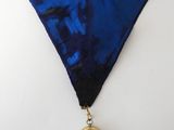blue ribbon with a gold medal attached to it on a white surface