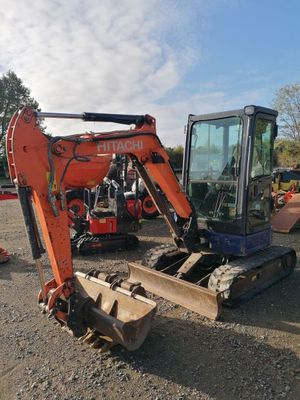une pelleteuse orange et noire posée au milieu d'un champ de terre