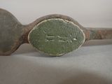 an old metal spoon with a green handle on a table
