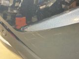 a close up of a car ' s front bumper with a reflection of a man in the background