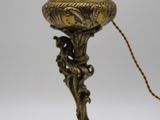 une lampe ancienne en laiton à laquelle est attachée une chaîne au niveau de son socle