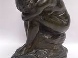 statue of a woman sitting on a rock with her head in her hands