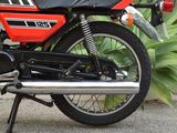 a red and black motorcycle parked in front of a plant