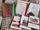 Plusieurs livres sont empilés sur un lit ; l'un d'eux a une couverture rouge et verte.