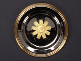 a black plate with a gold flower on it