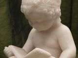 a small statue of a boy sitting on a rock