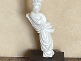 a statue of a woman holding a book on a marble table