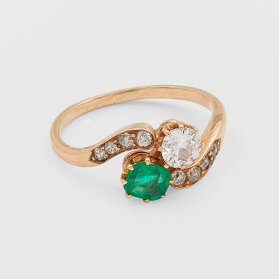 un gros plan d'une bague en or sertie d'une émeraude verte et de diamants blancs