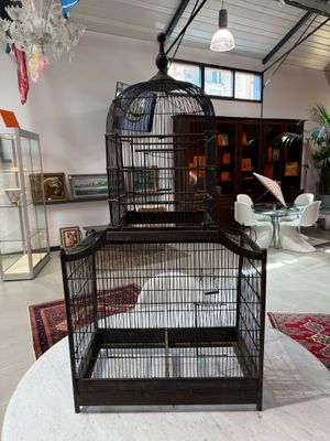 a bird cage sitting on top of a table in the middle of a room