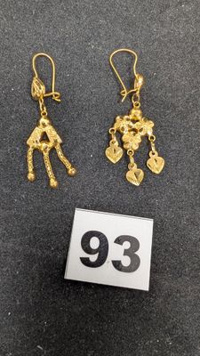 une paire de boucles d'oreilles en or représentant une femme tenant un sac à main