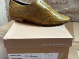 yellow snake skin shoes on a cardboard box with a brick wall in the background