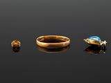 two gold rings and a ring with a blue stone on a black surface