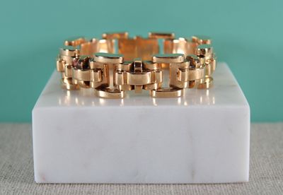 une image représentant un bracelet en or posé sur un bloc de marbre