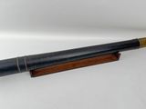 un vieux télescope posé sur un socle en bois, sur une surface blanche