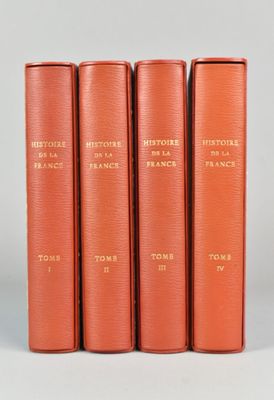 quatre livres rouges ornés de lettres dorées, posés sur une table