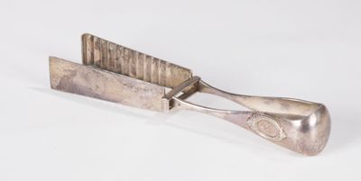 un petit objet argenté avec une poignée métallique sur une surface blanche
